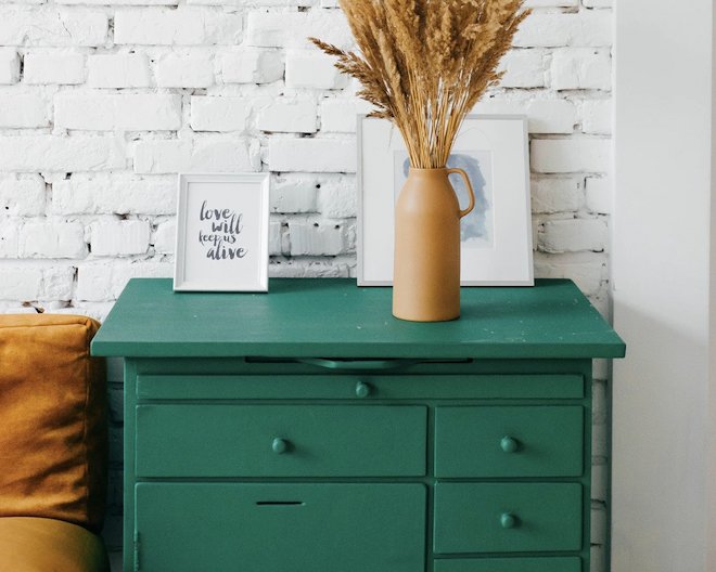 A green furniture with some portraits on top of it.
