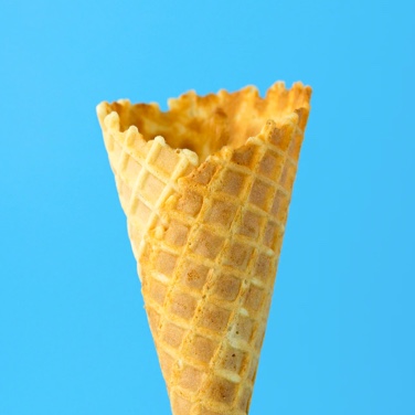 An ice-cream cone in front of a light blue background. 