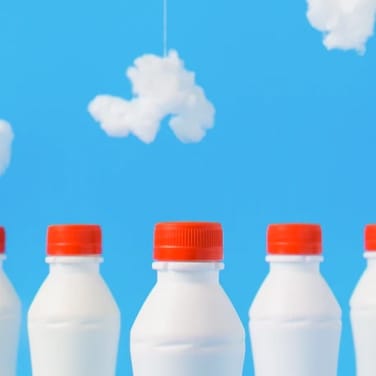 Three milk bottles in front of a cloudy background.